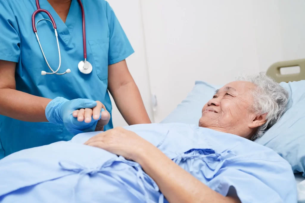 a hospice nurse compassionately holding a dying hospice patient's hands.
