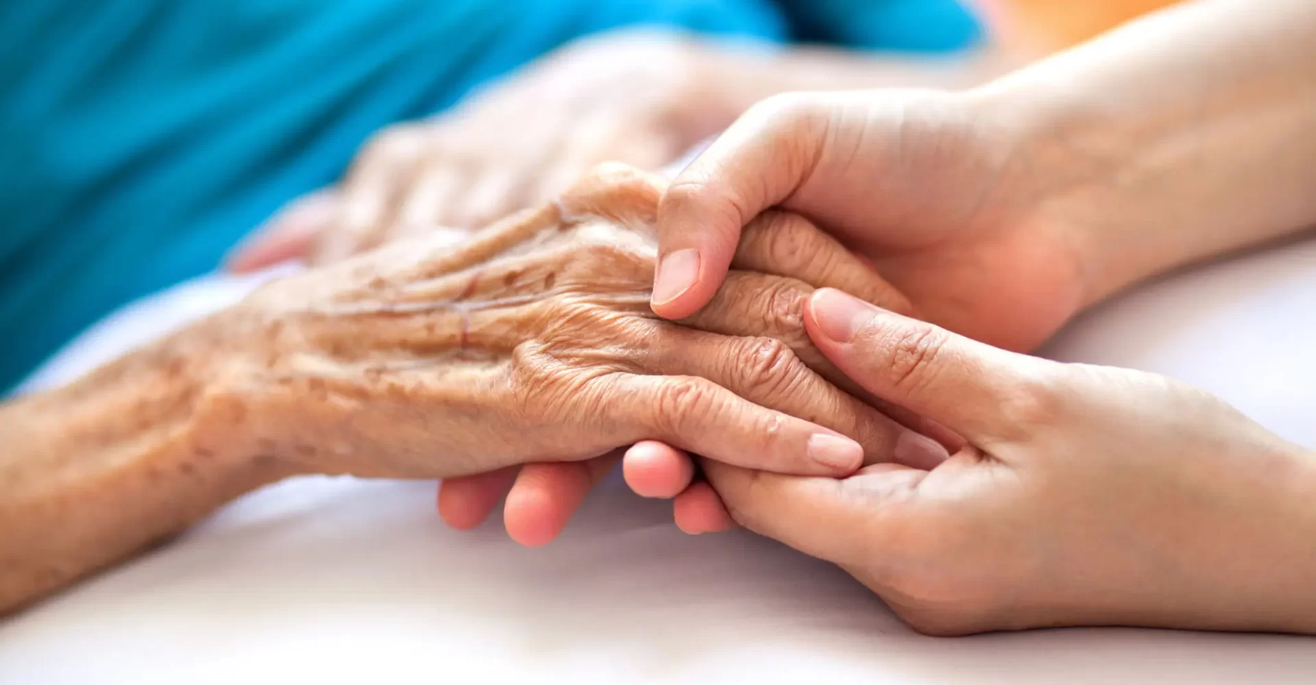 Hospice nurse holding a dying patient's hands compassionate